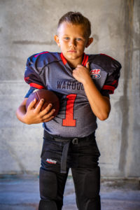 young child wearing a football uniform holding a football, portrait photographer, portrait photography, sports photographer, sports photography, outdoor photography, outdoor photographer